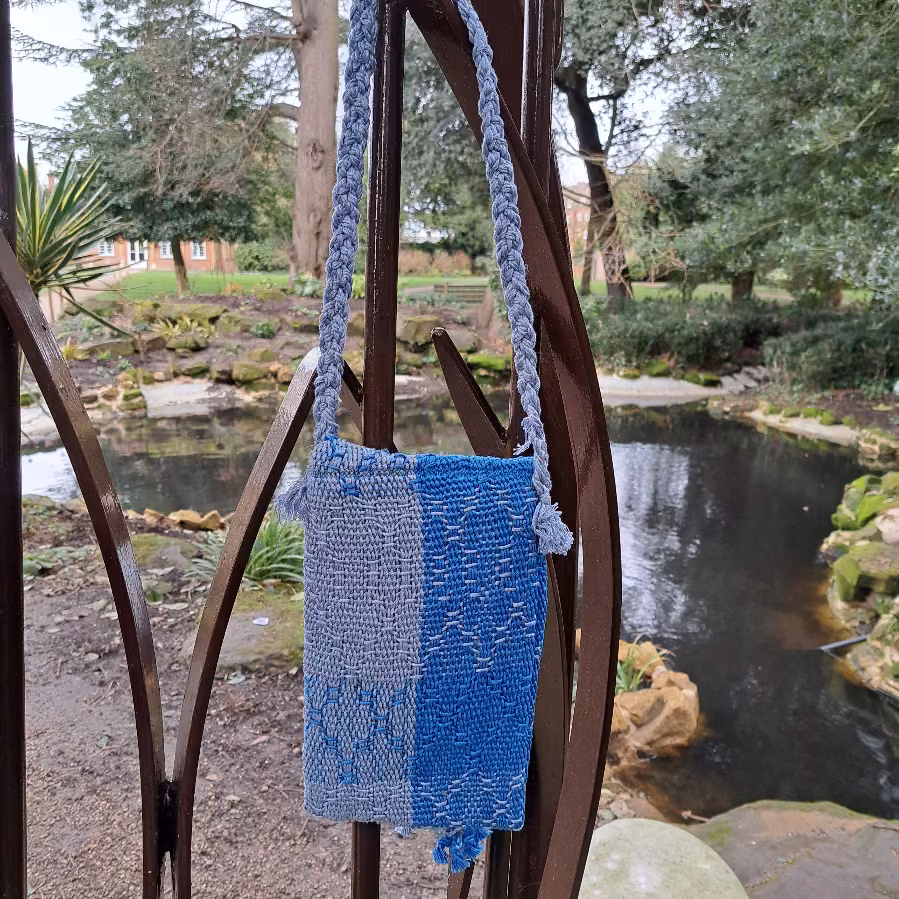 The back of the blue woven shoulder bag, showing pale and darker blue blocks