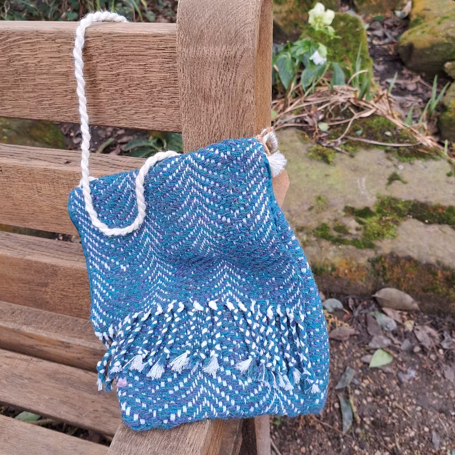 Blue Twill Bag hanging off the corner of bench