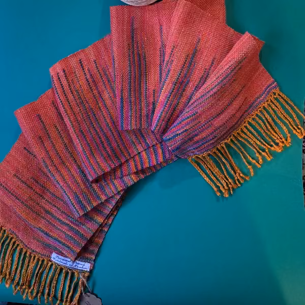 Coral pink scarf streaked with purple and blue, finished with a gold fringe