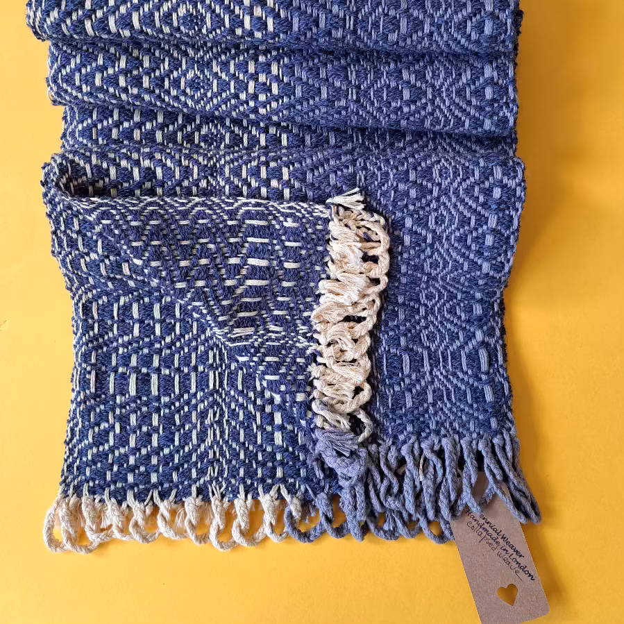 Deep blue scarf with a rippled surface and a cream textured band near the fringe